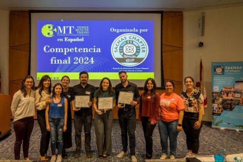 Group of people standing in front of a projection that reads Competencia final 2024, three people are holding awards