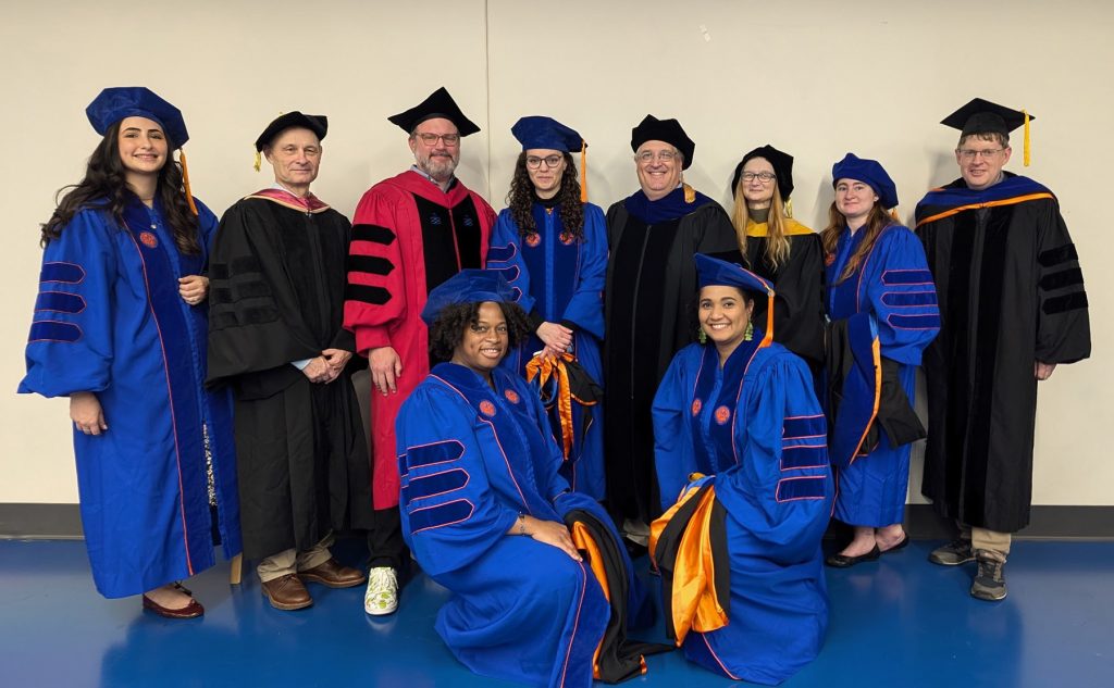 group photo of UF graduates and advisors in graduation caps and gowns 