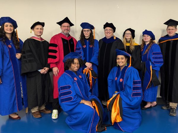 group photo of UF graduates and advisors in graduation caps and gowns