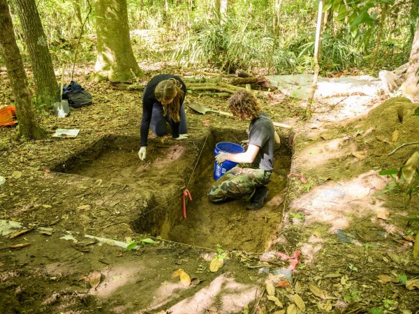 Two people dig archaeology pits.