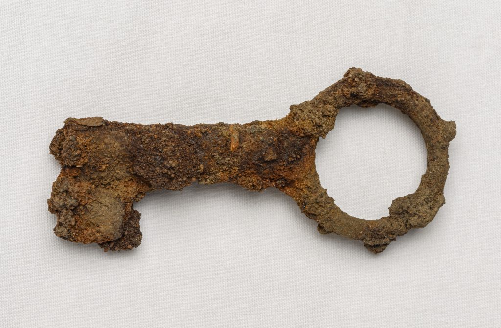 Close up of a rusted metal key on a white background.