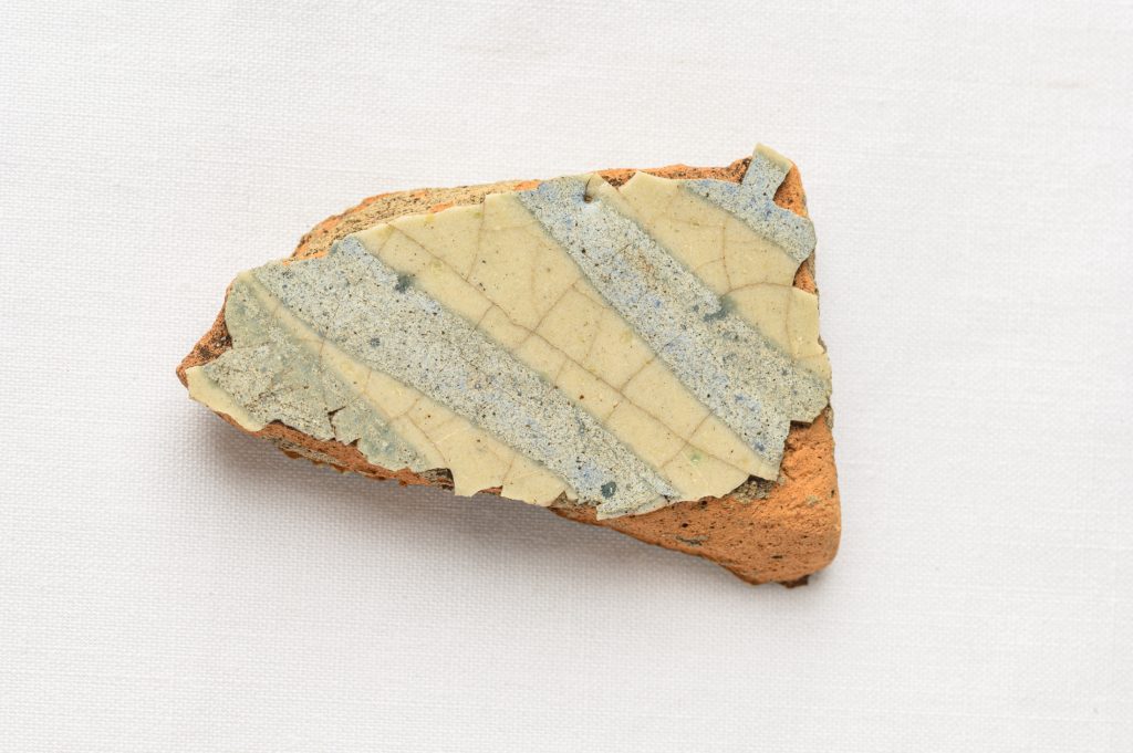 Piece of pottery with a white and bluish glaze against a white background.