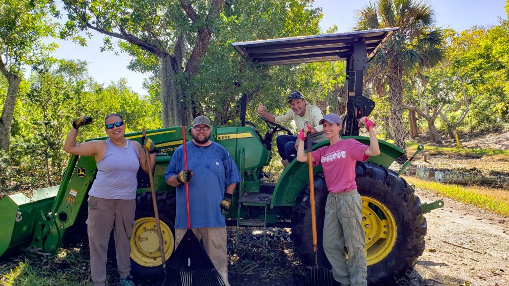 People outside posing in front and on a tractor.