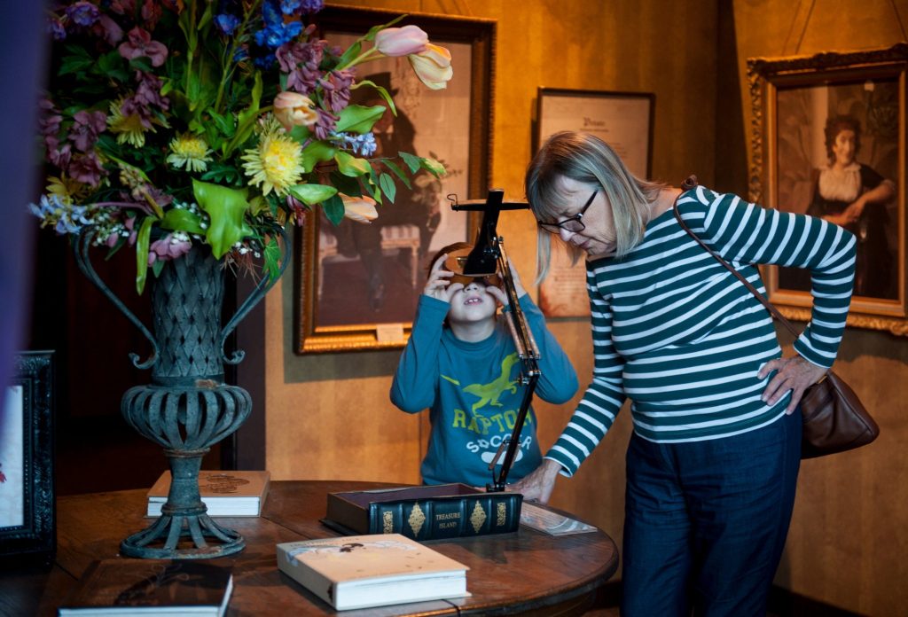 child using stereoscope while an adult reads the display set next to it
