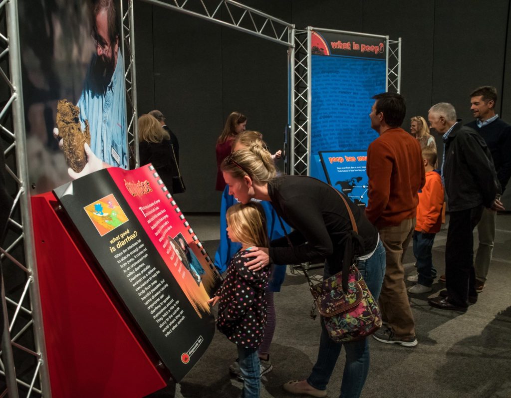 visitors, adult and children, read dispay information in the Scoop on Poop exhibit.