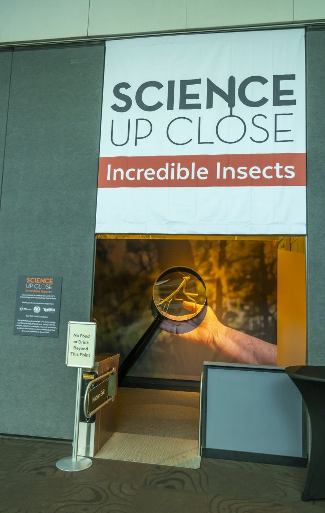 the entrance of a museum exhibit with a turnstile and a sign reading Science Up Close: Incredible Insects