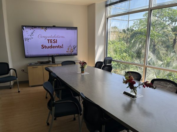 Wide shot of a computer screen and table. Computer screen has the banner that says Congrats TESI Students!