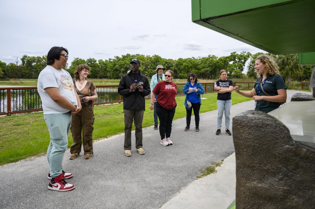 Wide shot of Fellows listening to Gabi as she talks about the environmental education kiosks and displays at the front of the park.