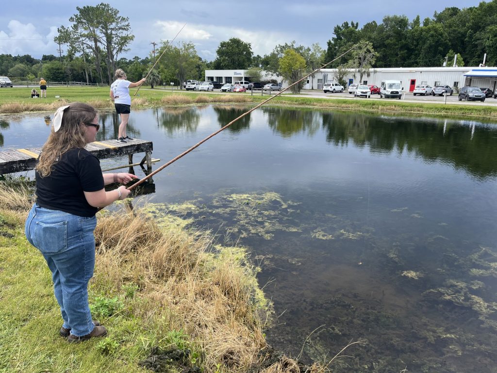 Wide shot of Laura Kleckner fishing in a pond.