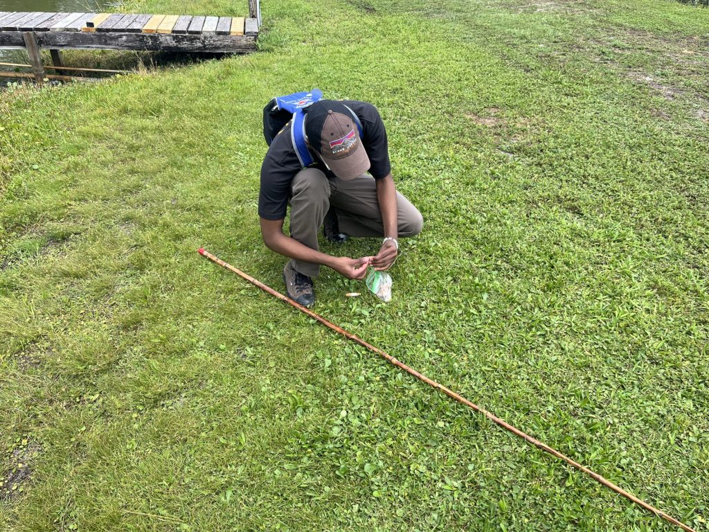 Joel is crouched on the ground examining the bait bag.