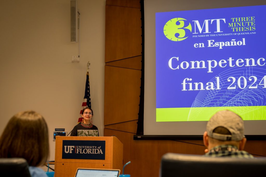A speaker introduces the three minute thesis competition at a podium.