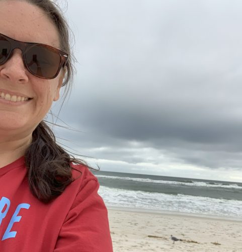 selfie on a beach, woman wearing sunglasses and red shirt